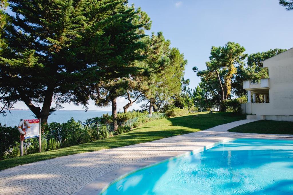 a swimming pool in front of a house with trees at Loving Tróia in Troia