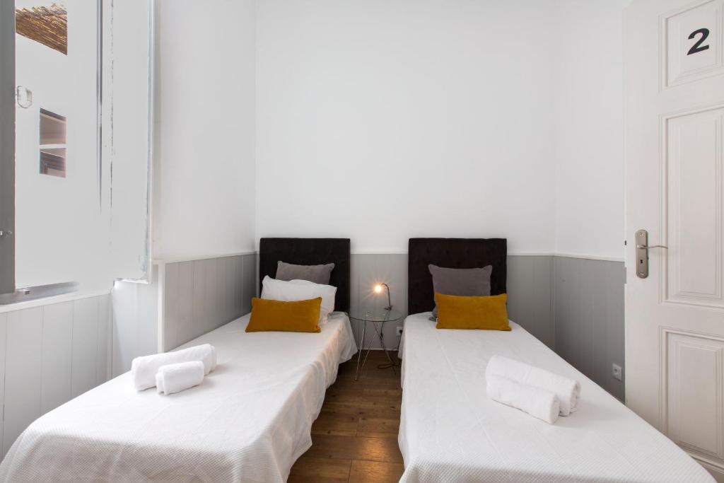 two beds in a room with white and yellow pillows at Faro Cosy Guesthouse in Faro