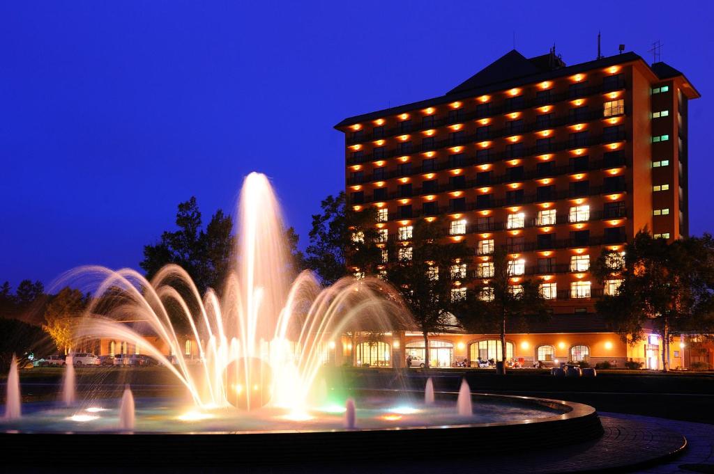 una fuente frente a un edificio por la noche en Tokachi Makubetsu Onsen Grandvrio Hotel en Obihiro