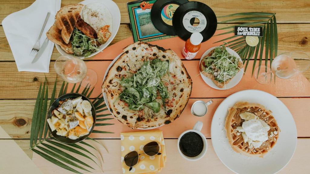 a table with plates of food on top of it at The Surfjack Hotel & Swim Club in Honolulu