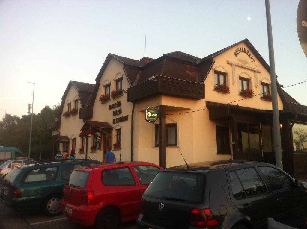 ein Gebäude mit Autos auf einem Parkplatz in der Unterkunft Panoráma Panzió in Tatabánya