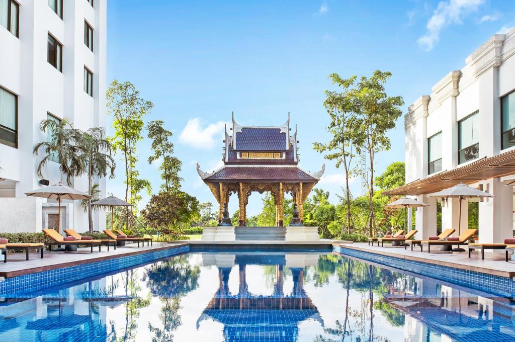 a swimming pool in front of a building with a gazebo at Mida Grande Hotel Dhavaravati Nakhon Pathom - SHA PLUS in Nakhon Pathom