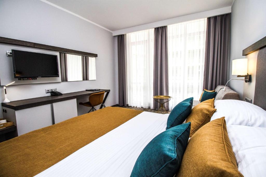 a hotel room with a large bed and a desk at Best Western PLUS Premium Inn in Sunny Beach
