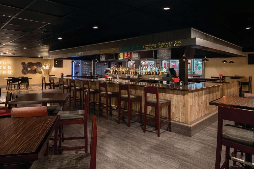 a bar in a restaurant with wooden tables and chairs at Ramada by Wyndham Indiana in Indiana