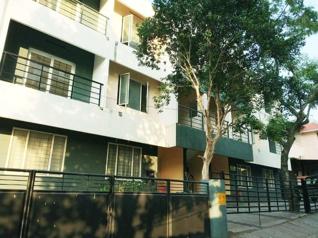 un edificio con un árbol delante en Honey Bee Serviced Apartments Trivandrum, en Trivandrum