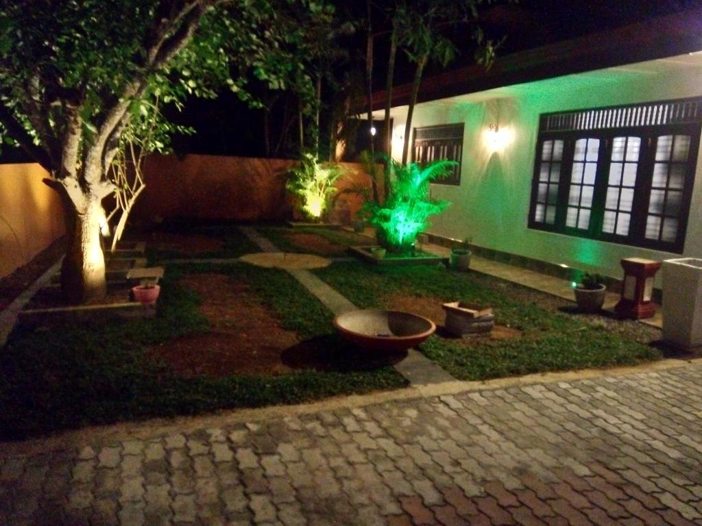 a garden at night with a building with green lights at Santosa Villa in Galle