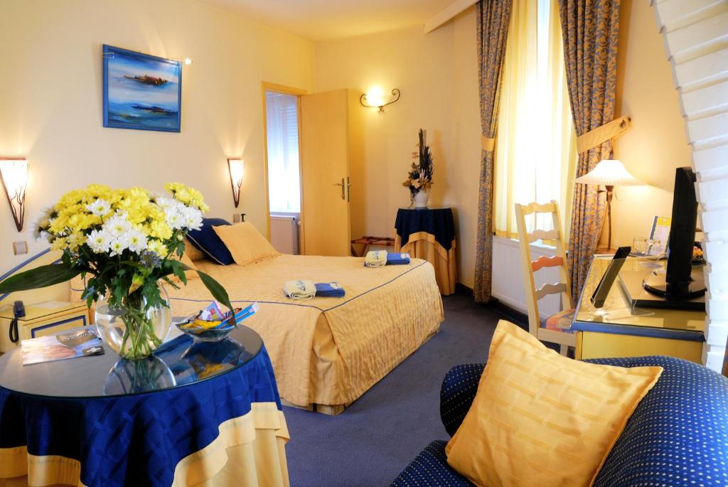 a hotel room with a bed and a vase of flowers on a table at Les Reflets Jaunes in Givet