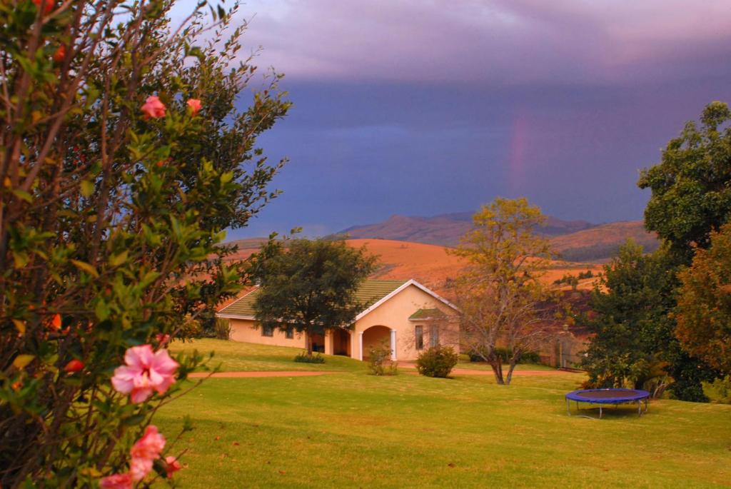 a rainbow in the sky over a house at Thaba Tsweni Lodge & Safaris in Graskop