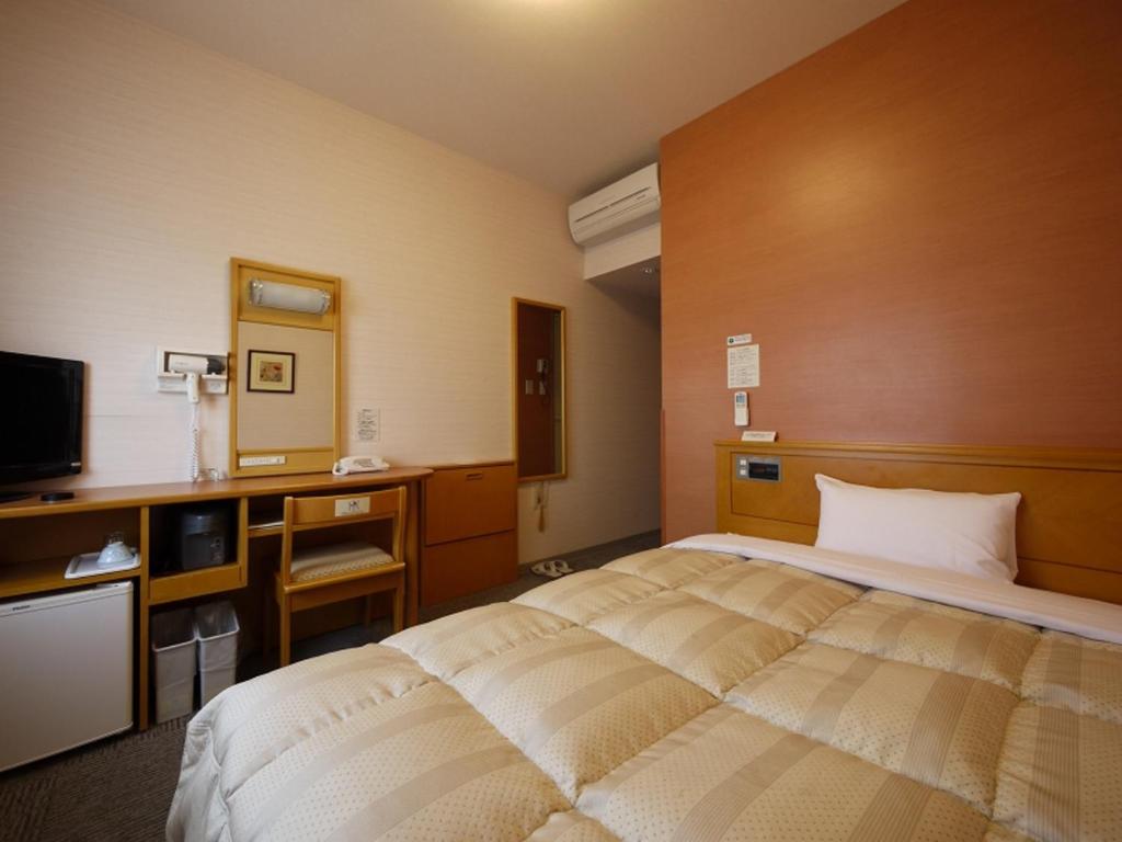 a hotel room with a bed and a television at Hotel Route-Inn Yamagata Ekimae in Yamagata