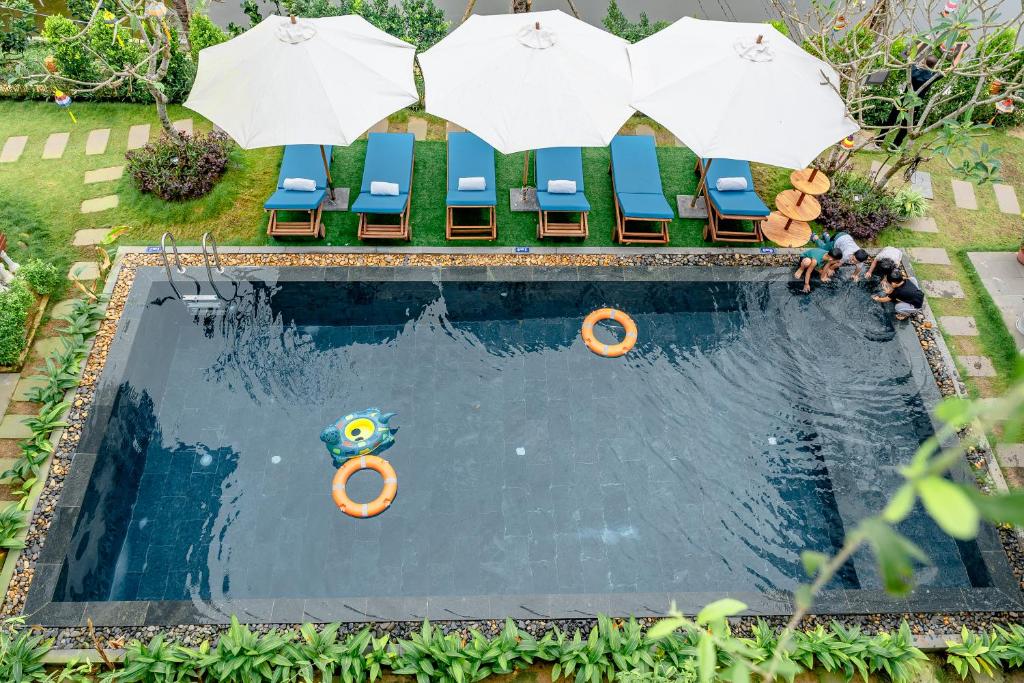 einen Blick über einen Pool mit Sonnenschirmen in der Unterkunft Hoi An Silverbell Villa in Hoi An