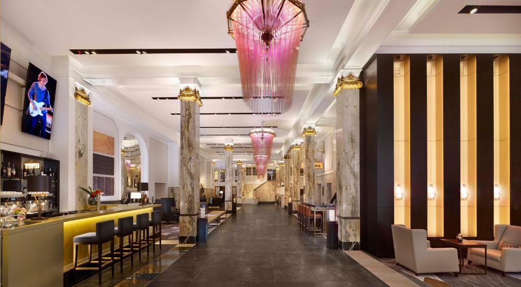 a lobby with a bar and a pink chandelier at Reichshof Hotel Hamburg in Hamburg