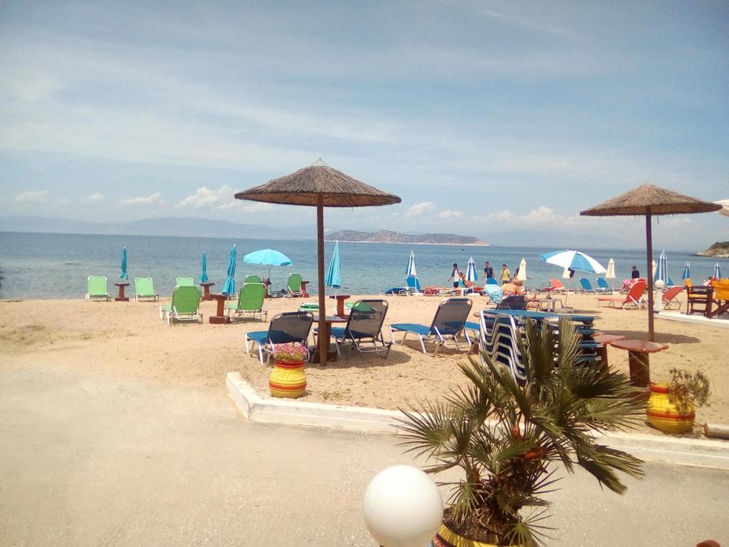 a beach with chairs and umbrellas and people on the beach at Villa Karanti in Limenas