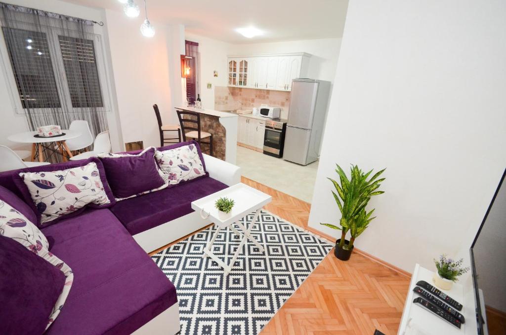 a living room with a purple couch and a kitchen at La Vida Kotor in Kotor