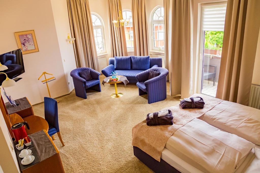ein Schlafzimmer mit einem Bett und Stühlen sowie ein Wohnzimmer in der Unterkunft Hotel-Restaurant Zur Krone in Löhnberg