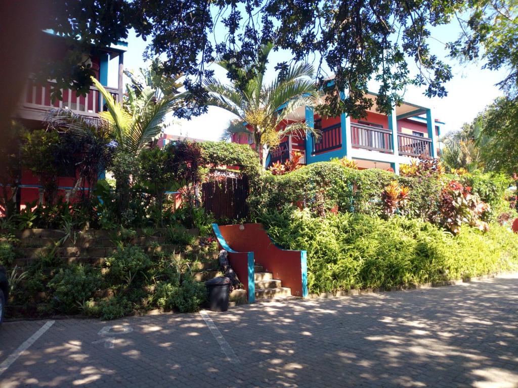 una casa con un edificio rojo y azul y árboles en Tri M Waves Lodge, en Ponta do Ouro