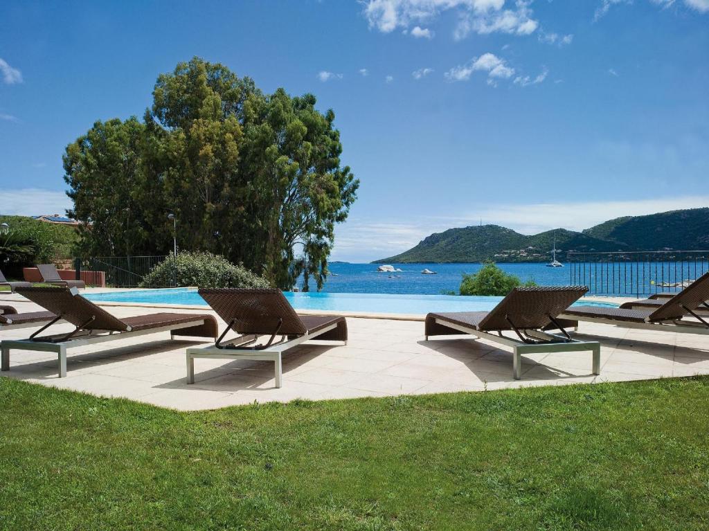 a row of lounge chairs sitting next to a swimming pool at Hotel Shegara in Porto-Vecchio