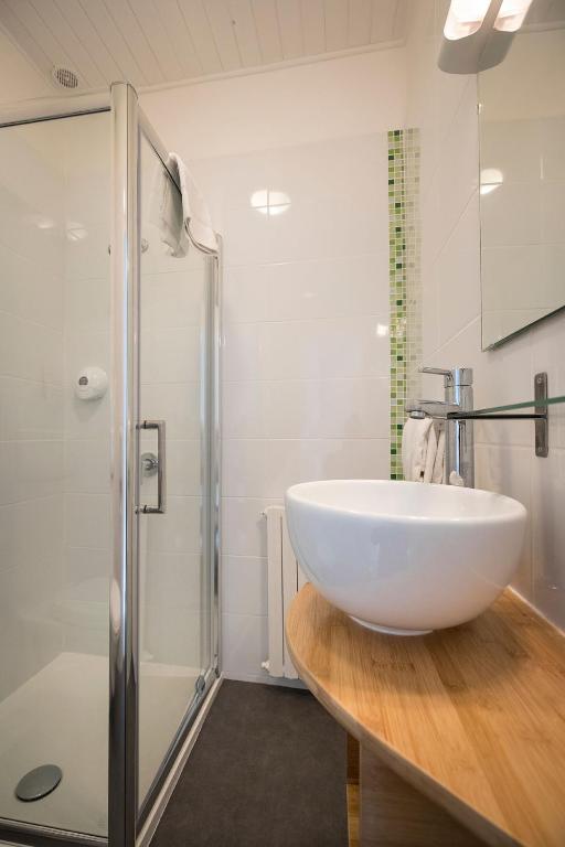 La salle de bains est pourvue d&#39;un grand lavabo blanc et d&#39;une douche. dans l&#39;établissement Hotel de Paris, à La Rochelle