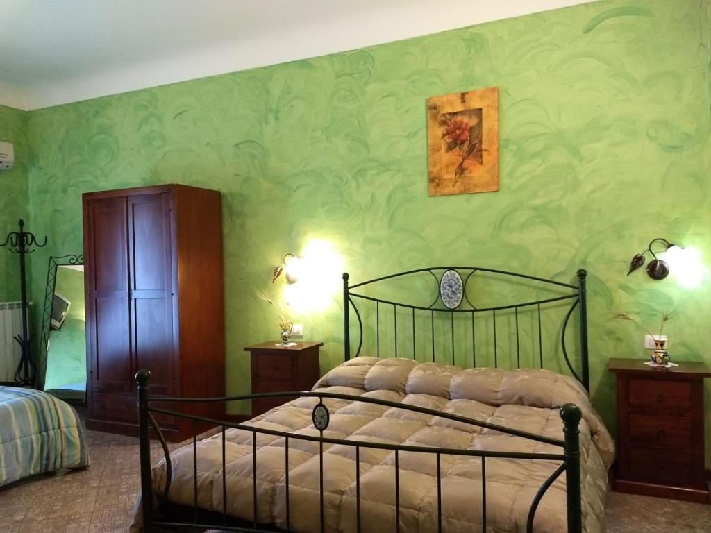 ein Schlafzimmer mit einem Bett und einer grünen Wand in der Unterkunft Palazzo Aprile in Caltagirone