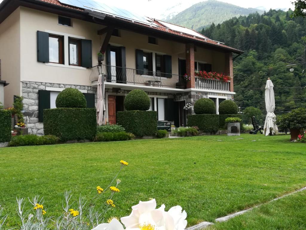 una casa con un patio verde con una flor blanca en B&B OLTRA, en Lamon