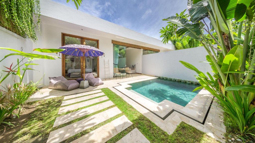 a house with a swimming pool and an umbrella at Anema Villa Seminyak in Legian