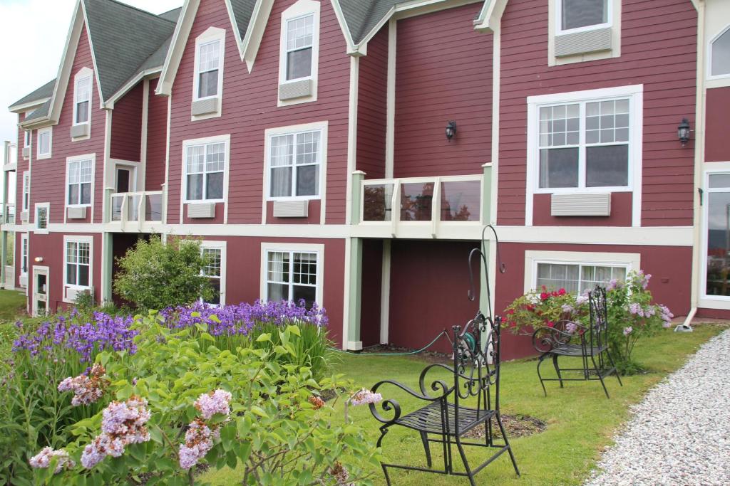 a large red house with two chairs in the yard at Lynwood Inn in Baddeck