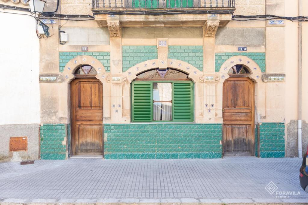 een gebouw met groene en houten deuren erop bij S'Estacio in Bunyola