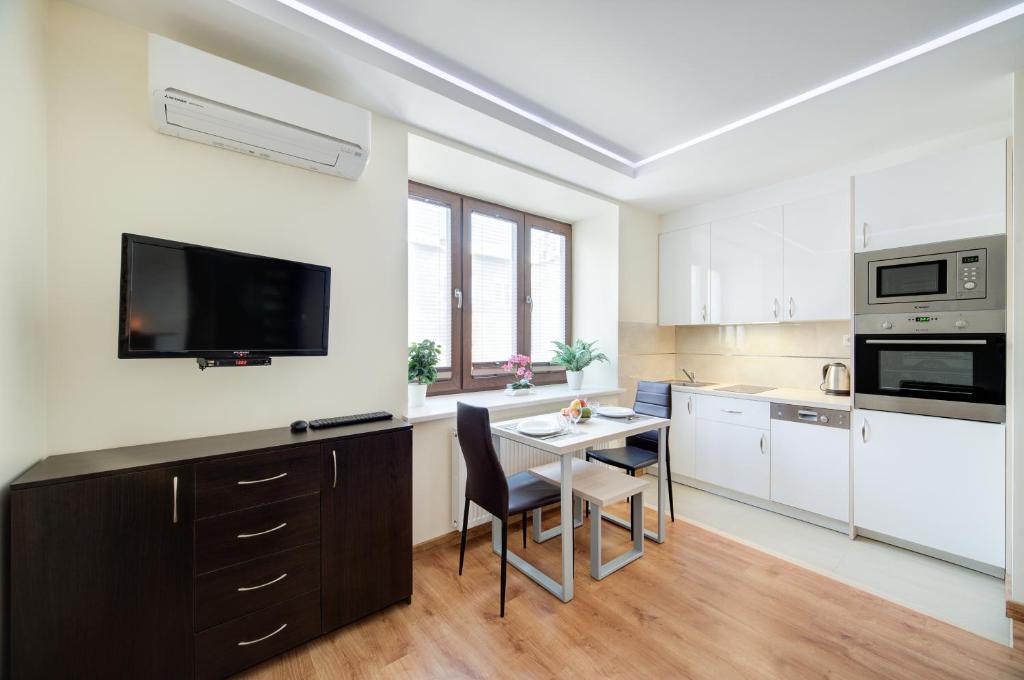 New Apartments Wieniawa في لوبلين: مطبخ مع طاولة وتلفزيون على الحائط