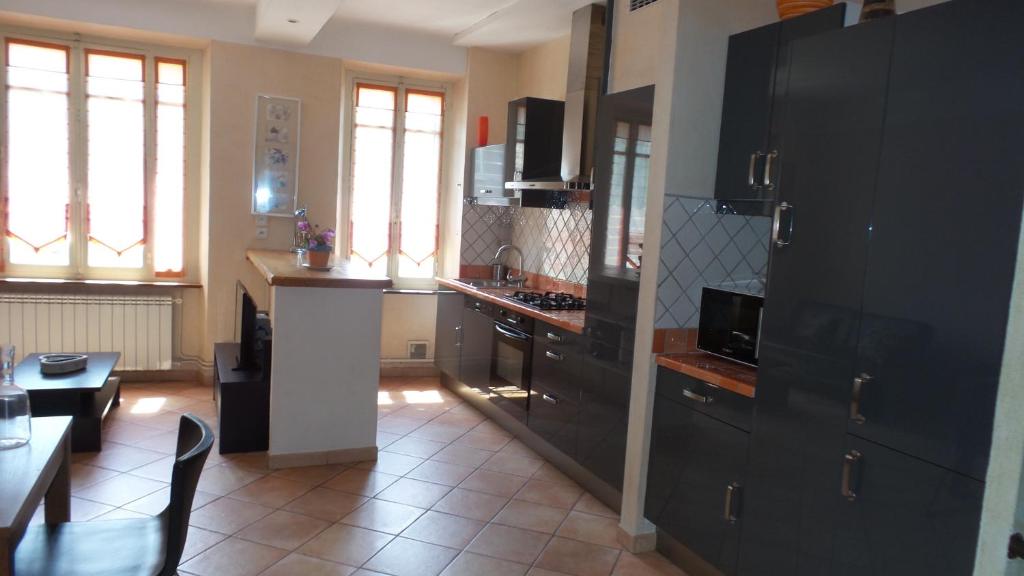 une cuisine avec des armoires noires et une table ainsi qu'une cuisine avec une cuisinière dans l'établissement spacieux logement face à la Cité Médievale, à Carcassonne