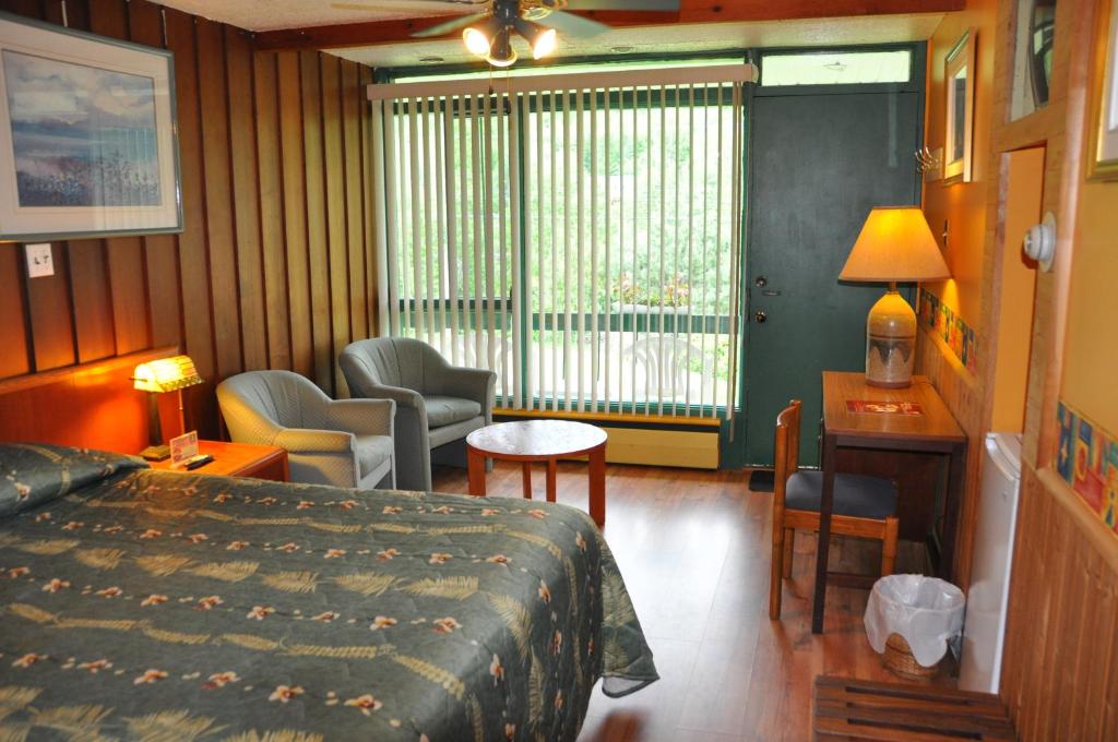 a hotel room with a bed and a living room at Le Boisé du Lac in Mont-Tremblant