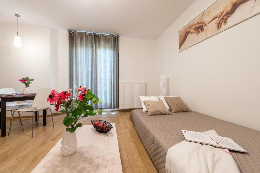 - une chambre avec un lit et une table ornée d'un vase de fleurs dans l'établissement P&O Apartments Zawiszy, à Varsovie