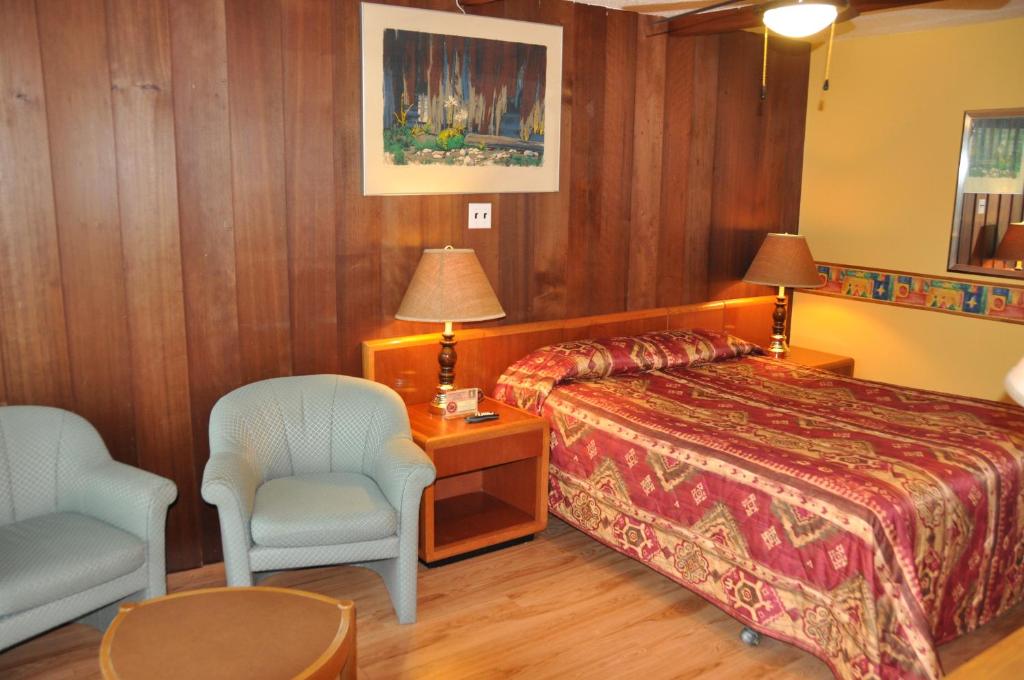 a hotel room with a bed and a chair at Le Boisé du Lac in Mont-Tremblant