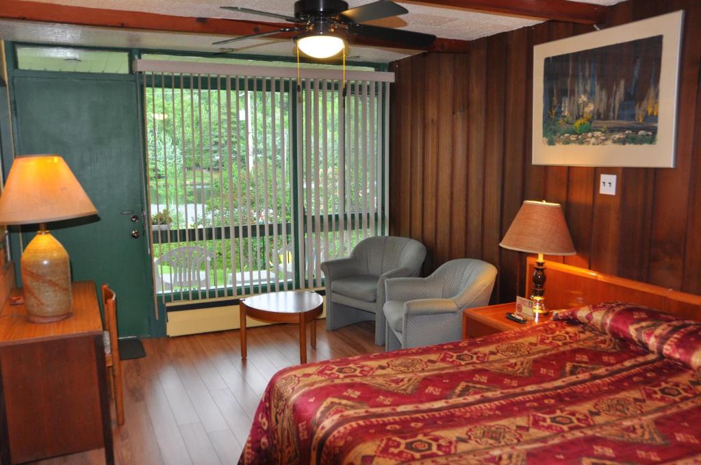a bedroom with a bed and a chair and a window at Le Boisé du Lac in Mont-Tremblant