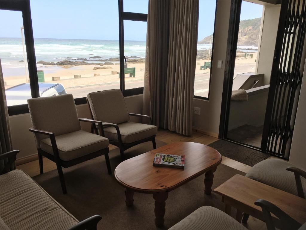 sala de estar con sillas, mesa y playa en Herolds Bay Accommodation - Coo-ee 2 en Herolds Bay