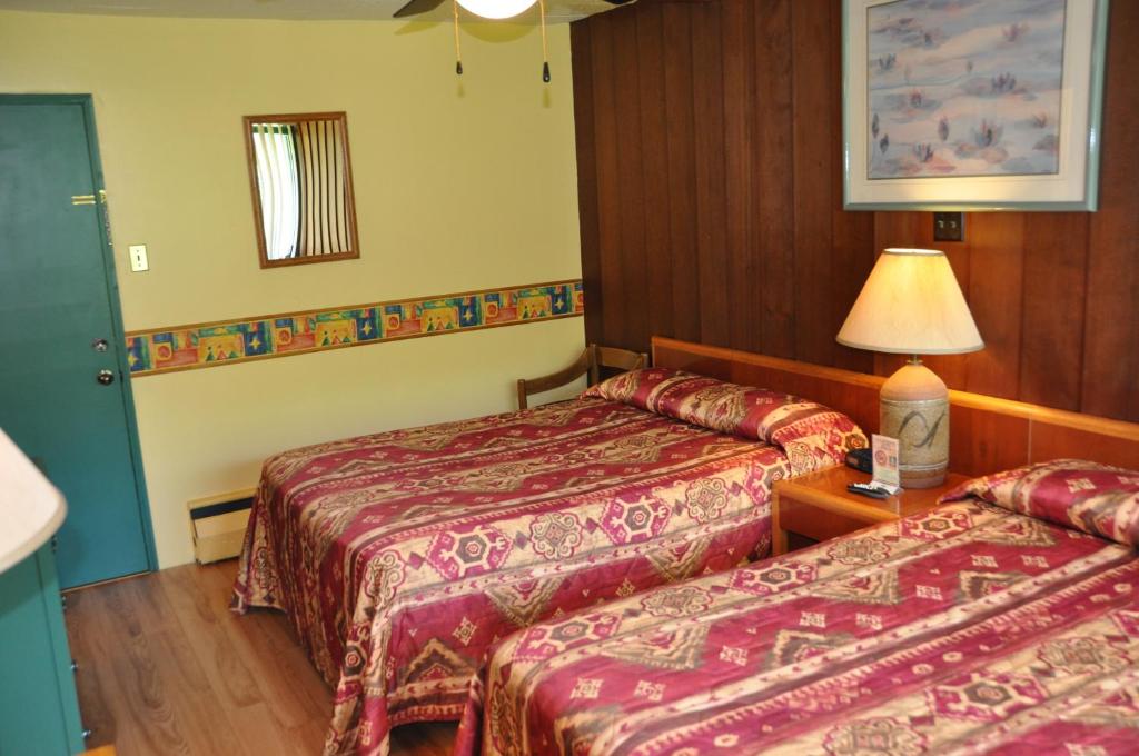 a hotel room with two beds and a lamp at Le Boisé du Lac in Mont-Tremblant