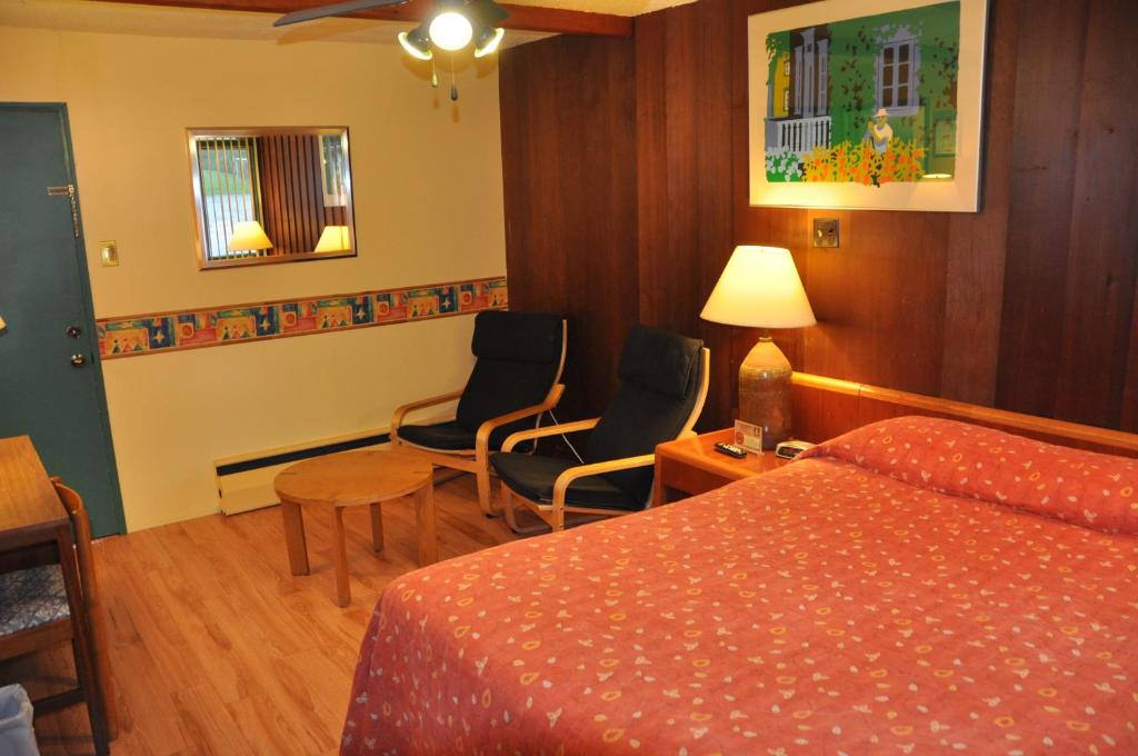 a hotel room with a bed and two chairs at Le Boisé du Lac in Mont-Tremblant