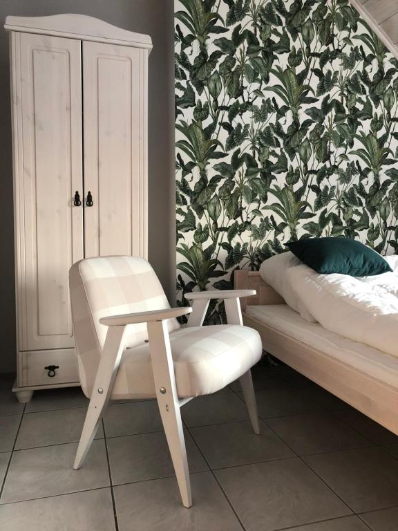 a bedroom with a bed and a chair and a wallpaper at Niewinne domki - Chianti in Żywiec