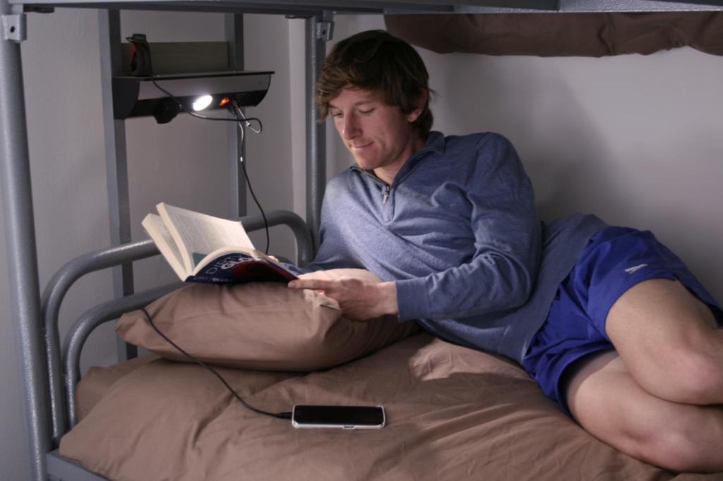 a man laying on a bed reading a book at Black Isle Hostel in Inverness