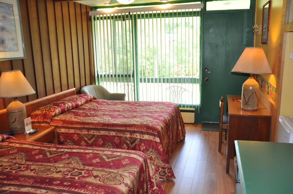 a hotel room with two beds and a desk and a window at Le Boisé du Lac in Mont-Tremblant