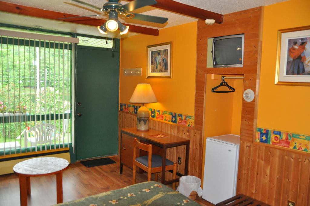 a room with a bed and a desk and a television at Le Boisé du Lac in Mont-Tremblant