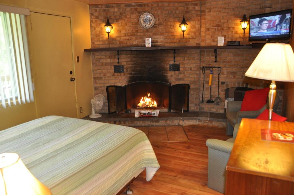 a bedroom with a fireplace and a bed in a room at Le Boisé du Lac in Mont-Tremblant