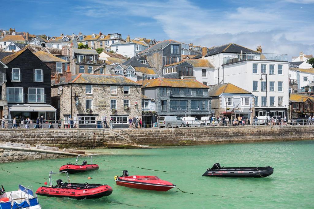 three boats are docked in the water near a city at Lifeboat Inn in St Ives