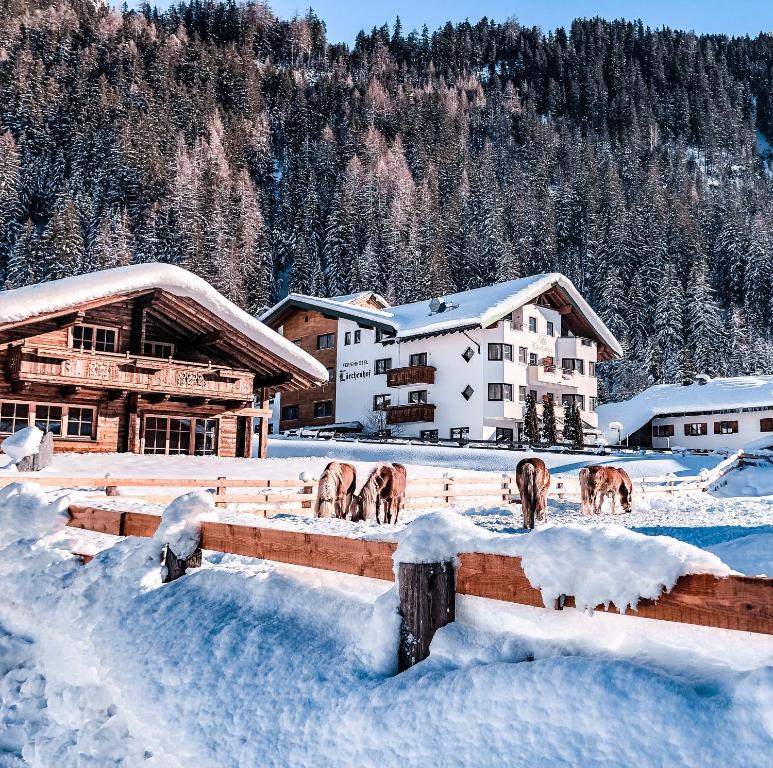 a group of deer standing in the snow in front of buildings at Hotel Lärchenhof in Kaunertal