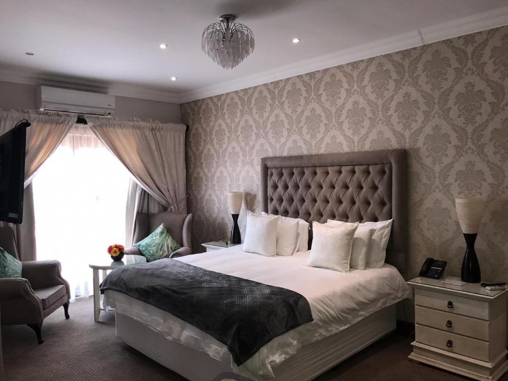 Un dormitorio con una cama grande y una ventana en Classique Grace Boutique Hotel, en Johannesburgo