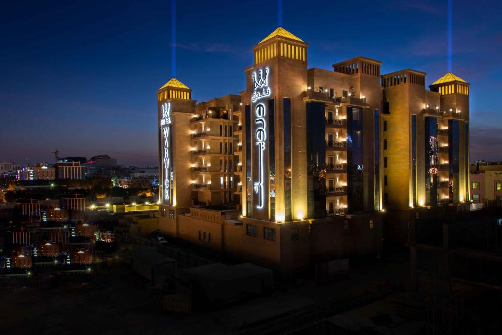 a large building with lights on it at night at Warwick Al Khobar in Al Khobar