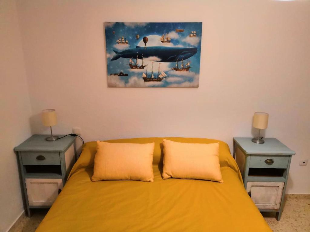 um quarto com uma cama amarela com duas mesas de cabeceira em Vivienda cercana a la playa con todas las comodidades em Tarifa