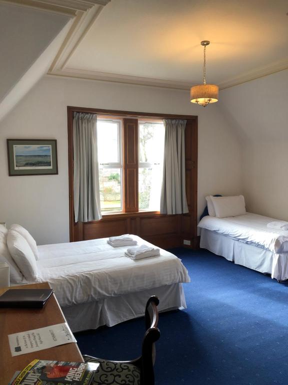 ネアンにあるWesterlea Hotel Nairnのベッド2台、デスク、窓が備わるホテルルームです。
