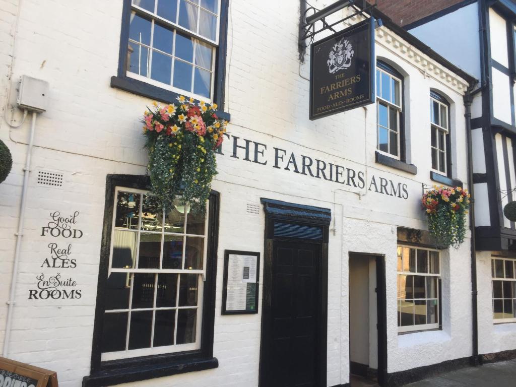 a white building with flowers on the front of it at FARRIERS ARMS in Worcester