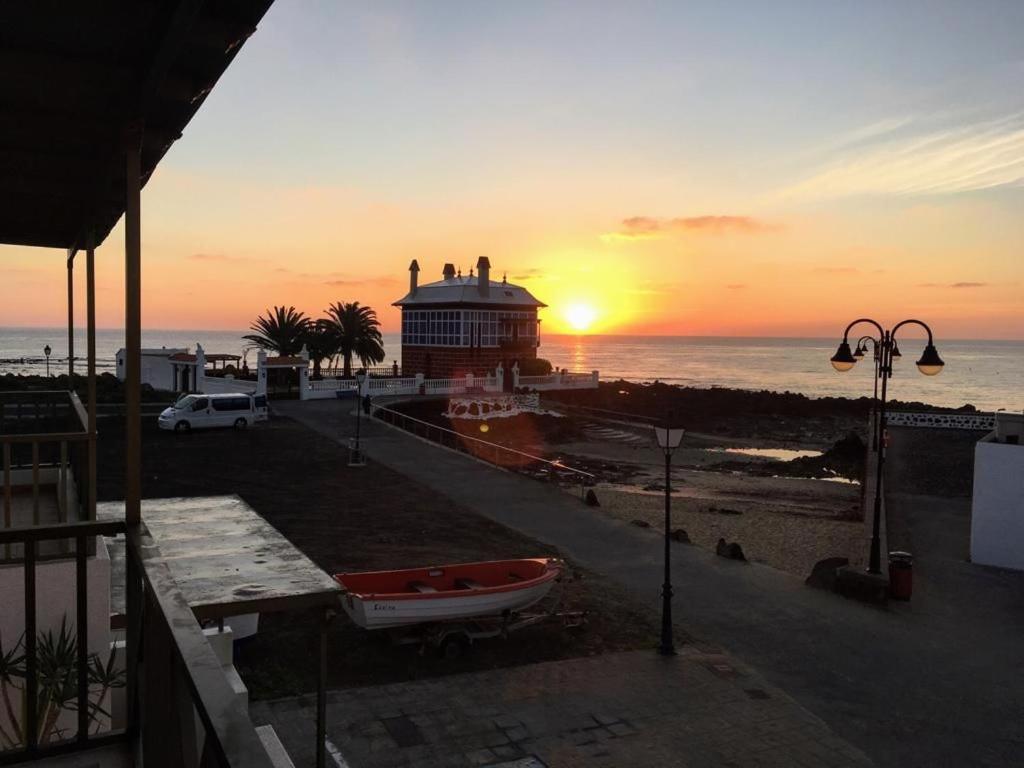 a building on the beach with the sunset in the background at Apartamento El Muelle in Arrieta