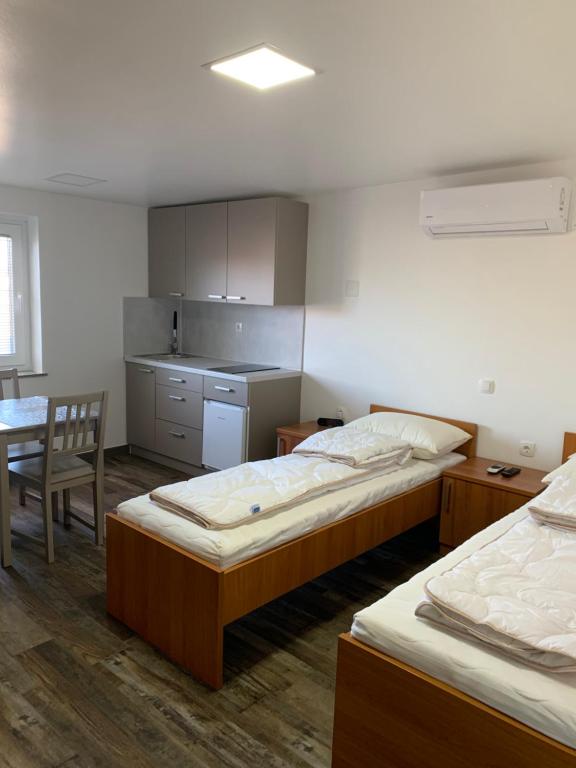 Habitación con 2 camas, mesa y cocina. en Apartman Decorus en Maribor