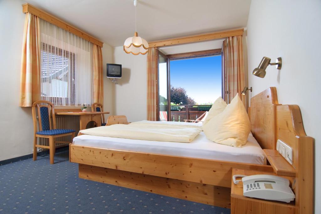 ein Schlafzimmer mit einem Holzbett und einem Fenster in der Unterkunft Hubertushof in Latschach ober dem Faakersee